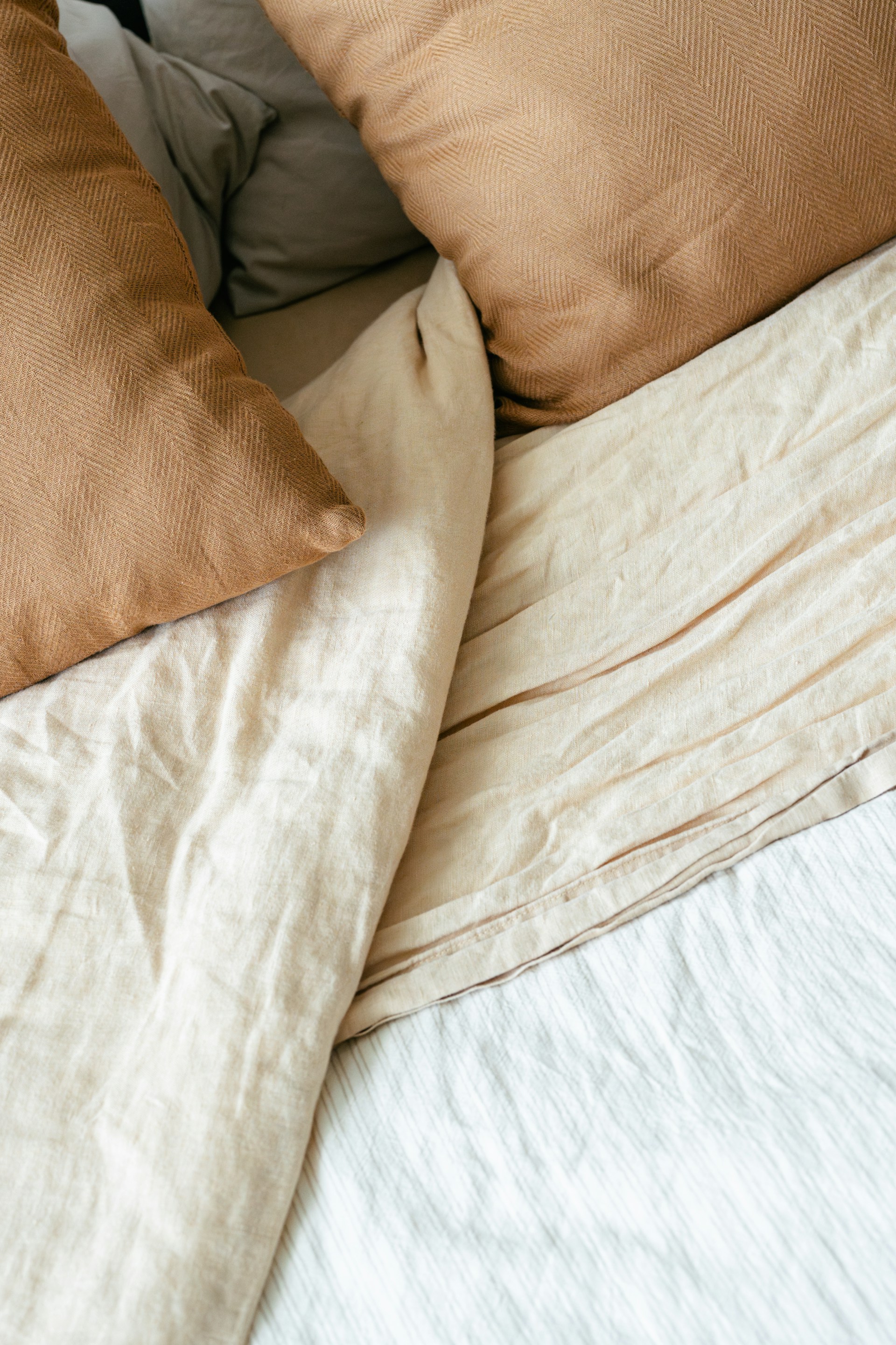 Bett mit Kissen und Decken in warmen Erdtönen