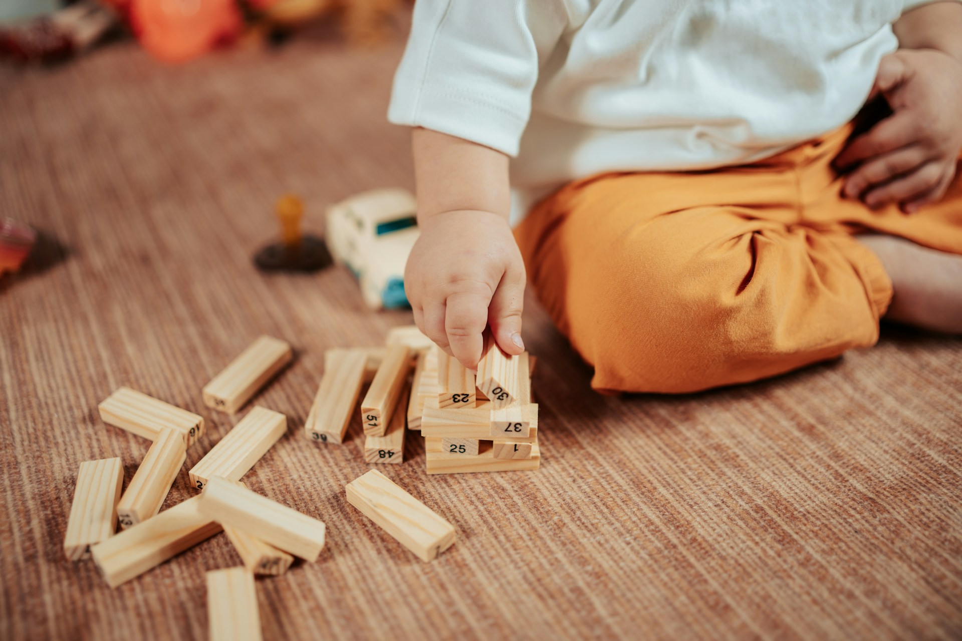 Kleinkind spielt auf dem Boden mit Holzbausteinen