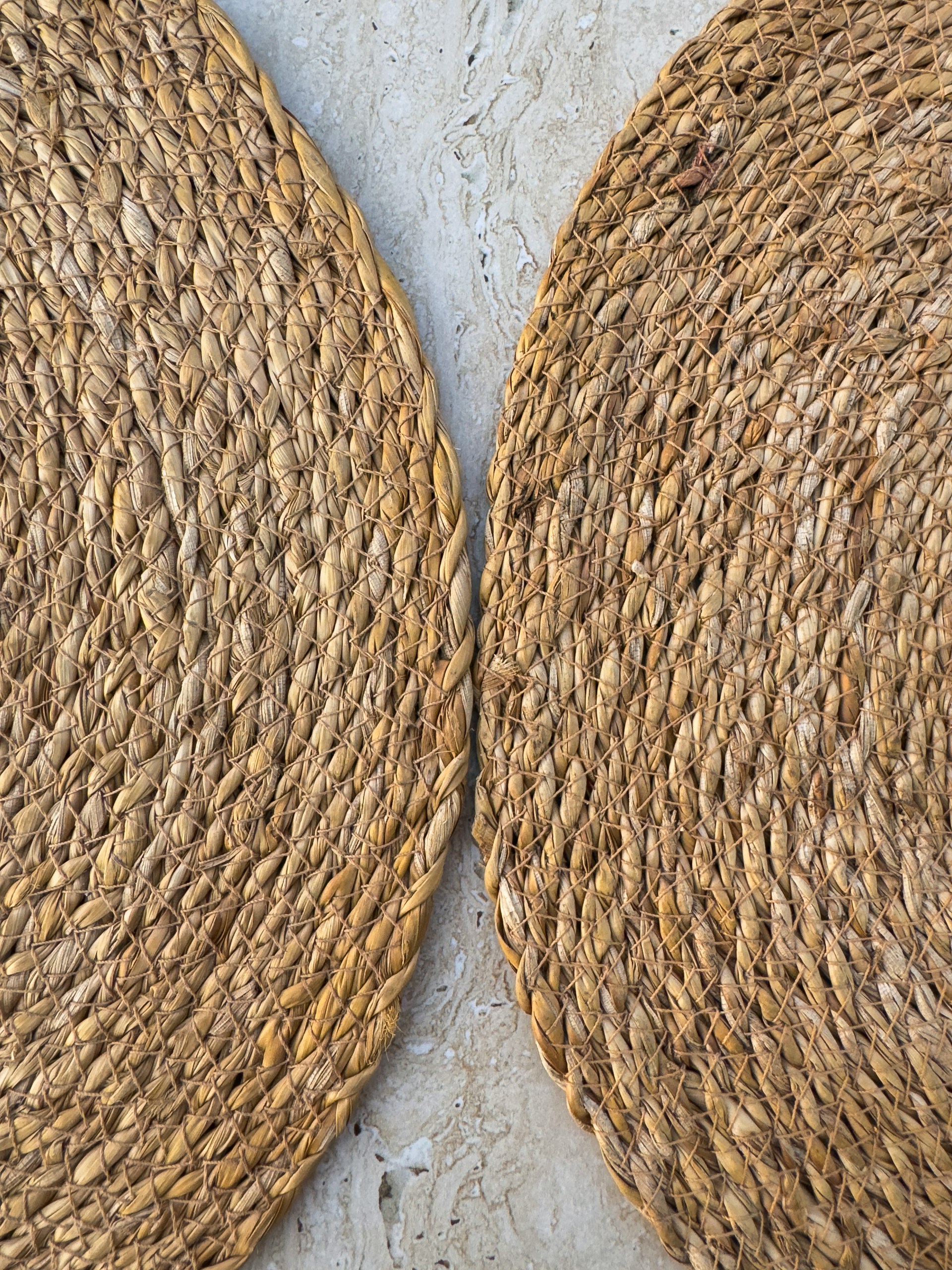 Zwei geflochtene Platzsets aus Naturfaser auf hellem Stein