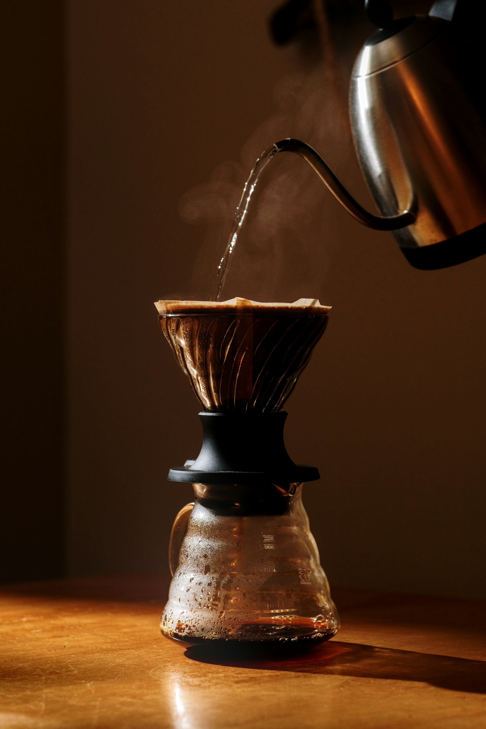 Heißes Wasser wird aus einem Edelstahl-Wasserkocher in einen Kaffeefilter gegossen
