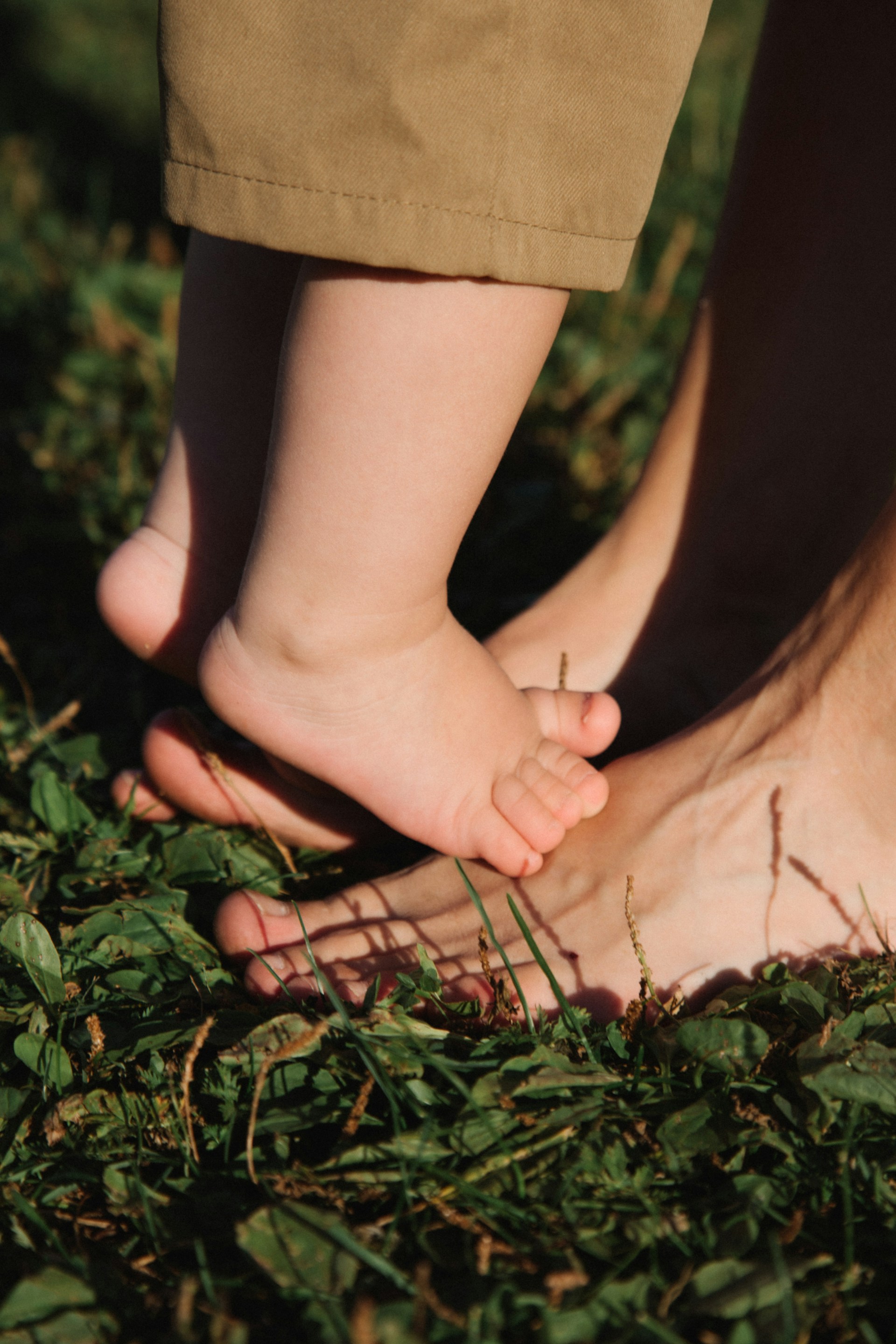 Kind steht mit nackten Füßen auf den Füßen seiner Mama - Nähe im Mama-Alltag