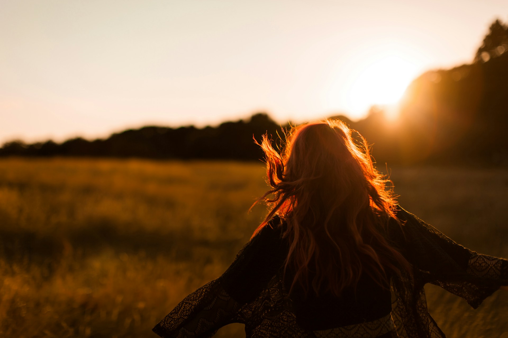 Frau geht ins Sonnenlicht, lange Haare im Gegenlicht