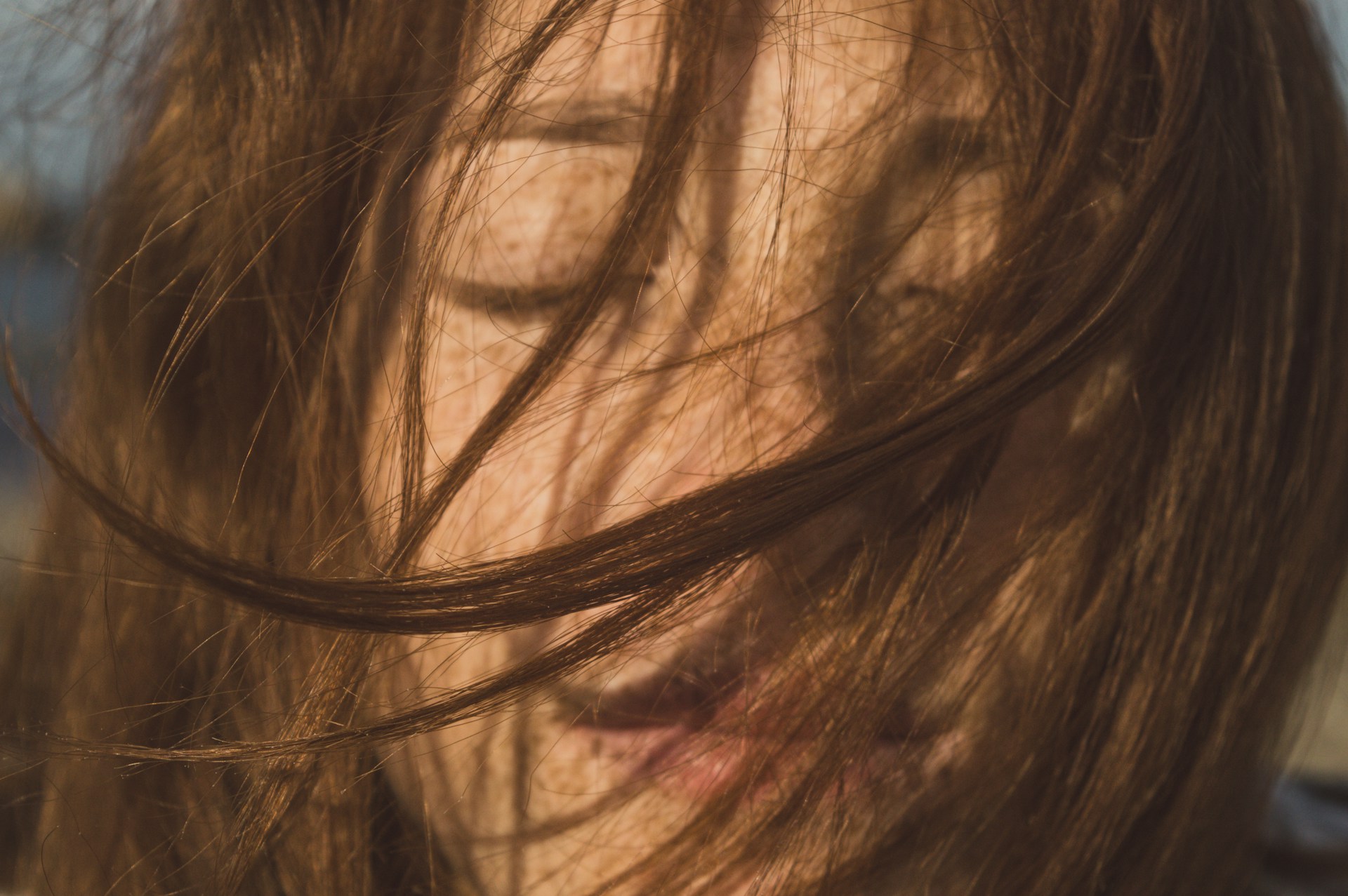 Frau mit windverwehten Haaren, Augen geschlossen